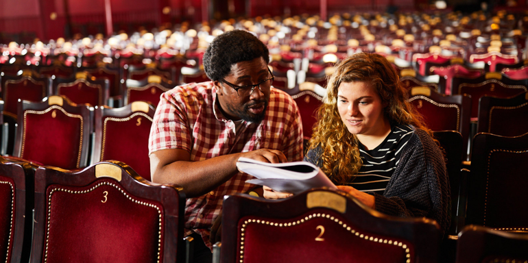 Two People In Theatre Looking At A Programme